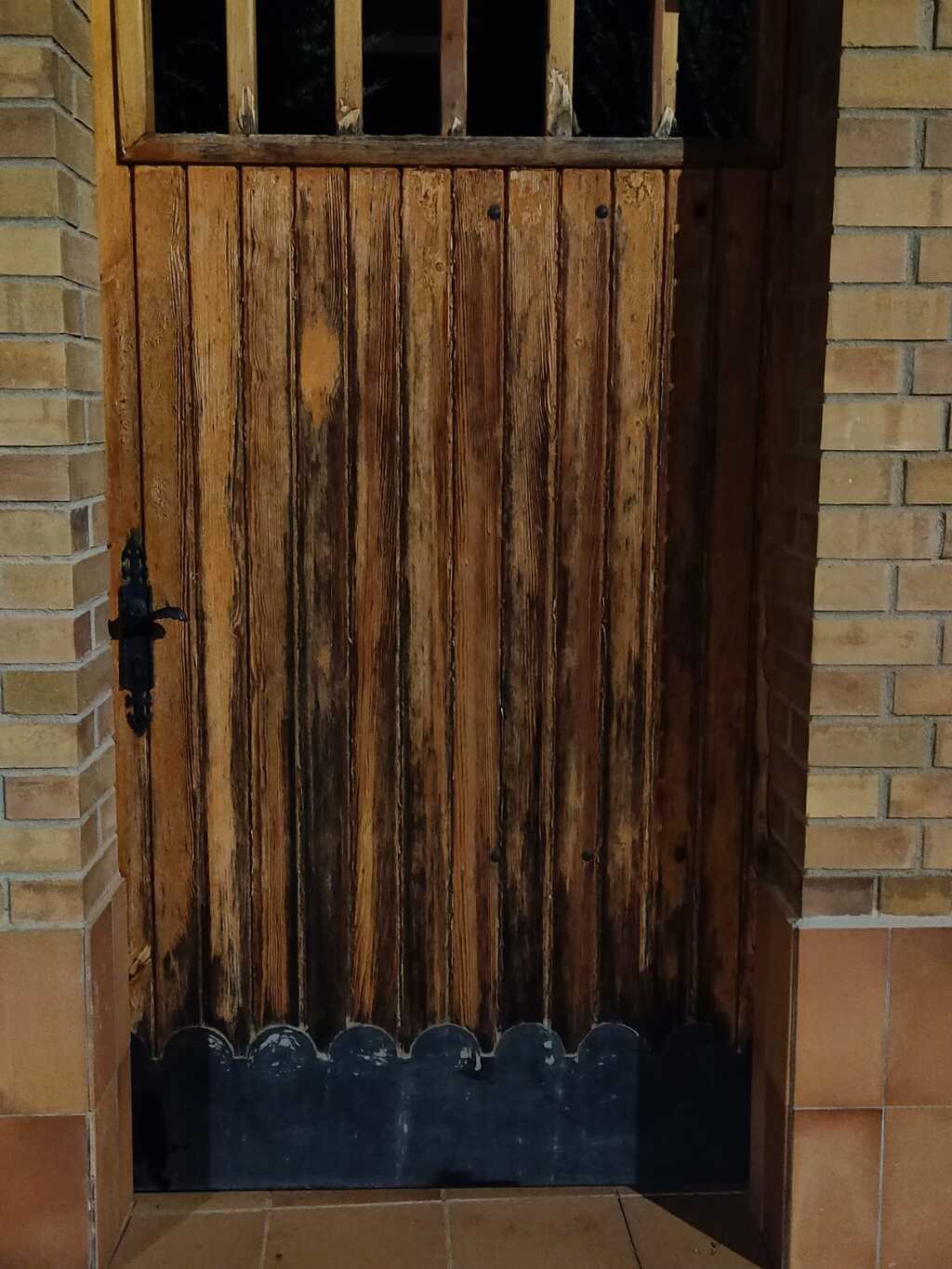 Detalle de la puerta de entrada de madera deteriorada por el tiempo Topi Lleida