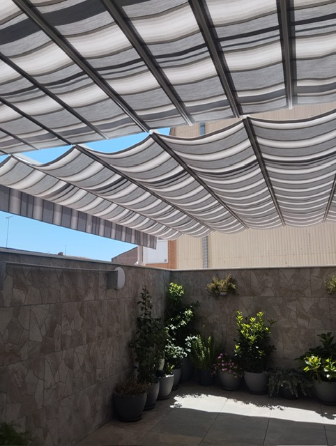 Terraza cubierta con la nueva lona de pérgola a rayas grises y blancas