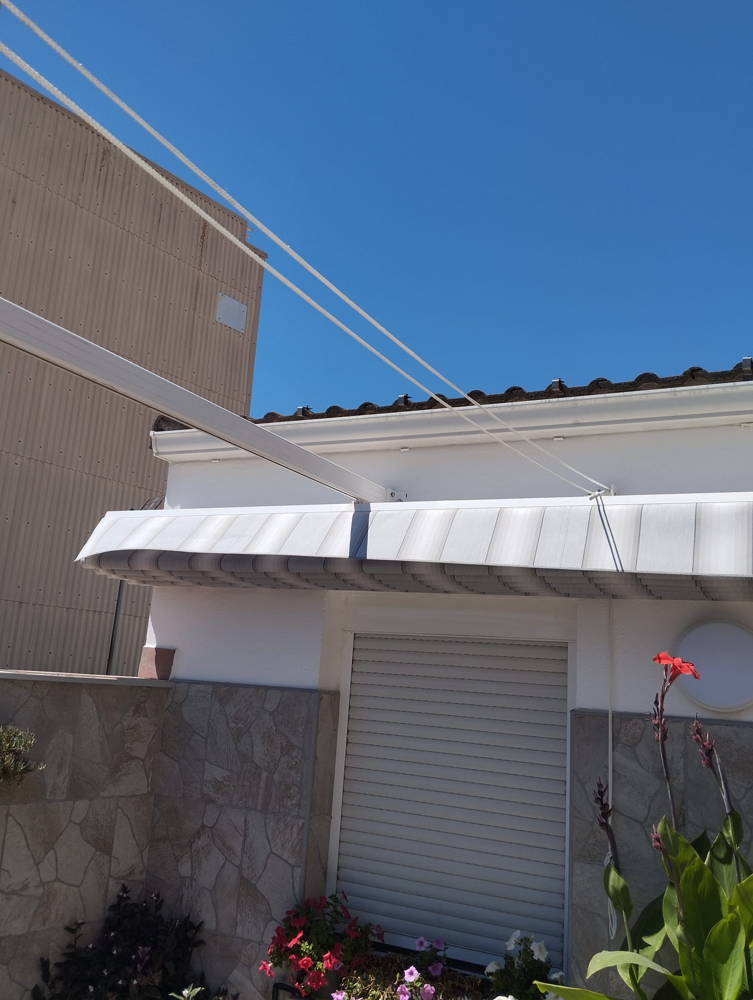 Lona de pérgola recogida con cuerda blanca y estructura de aluminio