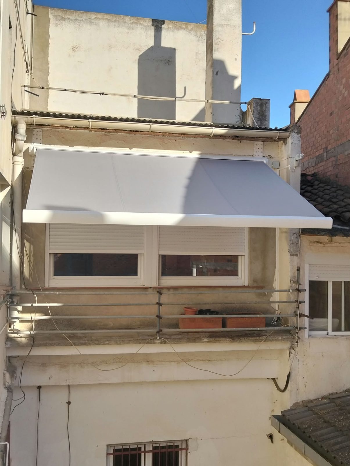 Toldo cofre lacado en blanco con lona acrílica extendido sobre dos ventanas en Lleida